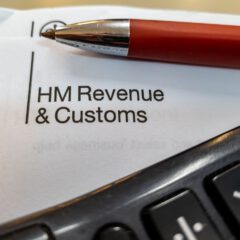 A close-up of an HM Revenue & Customs document with a red pen and part of a calculator visible in the foreground.